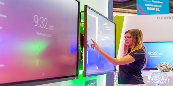 A woman interacting with a Data Projections interactive screen at a trade show
