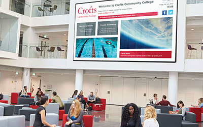 A large digital wall hanging above an atrium inside a business building