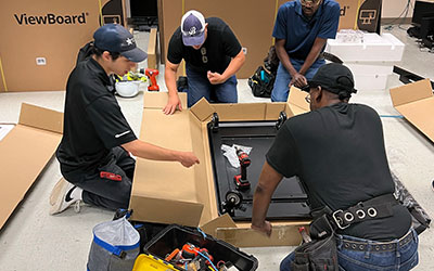 The Data Projections team unpacking a new monitor