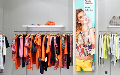 A video wall integrated into a retail store next to clothing racks