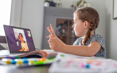A child on a virtual conference call with her teacher learning math