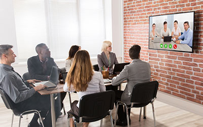 Business people sitting in a brick room having a conference call using Data Projections' AV over IP solutions