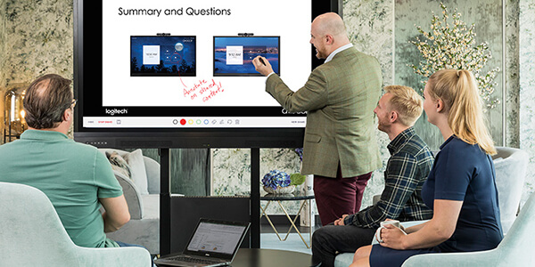 A man writing notes on an interactive display screen in front of clients