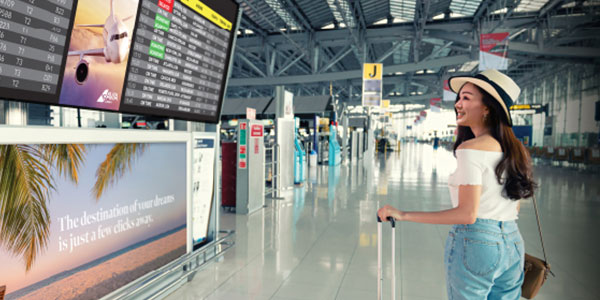 A woman reviewing flight details on a Christie digital screen in an airport terminal