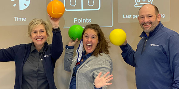 Data Projections' team members holding up foam balls in front of a game screen