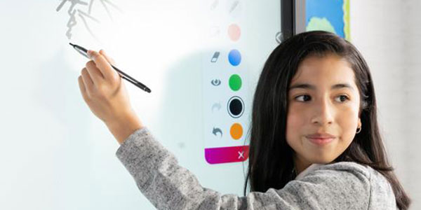 A female student drawing on a large interactive screen