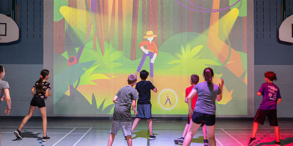 Kids in gym playing a dance game on a 3D wall projector