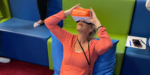 A woman sitting back and looking up into a VR headset