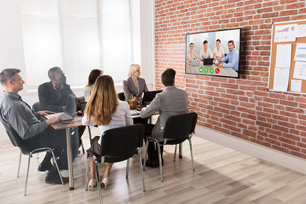 Team members sitting in a brick room on a video conference call
