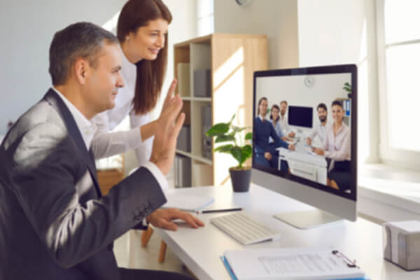 Data Projections specialists waving at on a conference call to full boardroom of clients