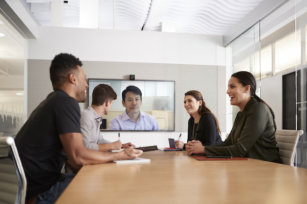 People sitting around a conference room table with streaming equipment set up for a video call